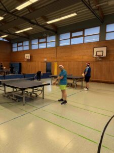 In Tischtennishalle spielen Personen mit Weihnachtsmannmütze
